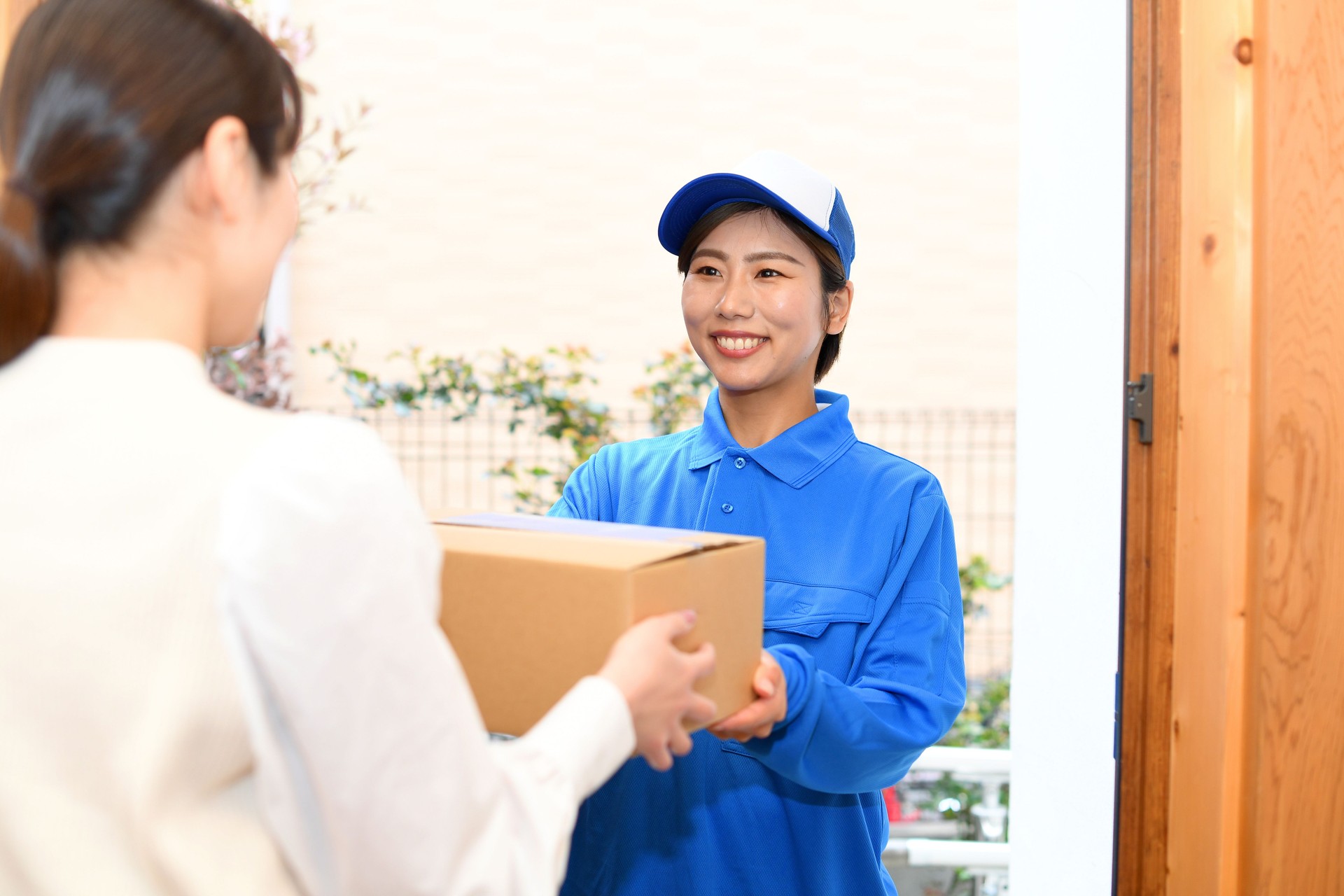 A delivery man delivering a package and a woman receiving it